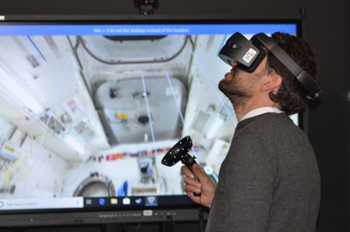 Ein Mann trägt eine VR-Brille und schaut sich um.