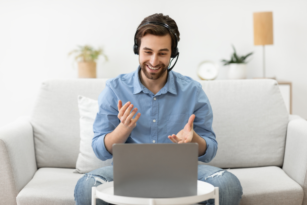 Ein Mann sitzt vor einem Laptop und folgt einem Webinar oder einem Webcast.