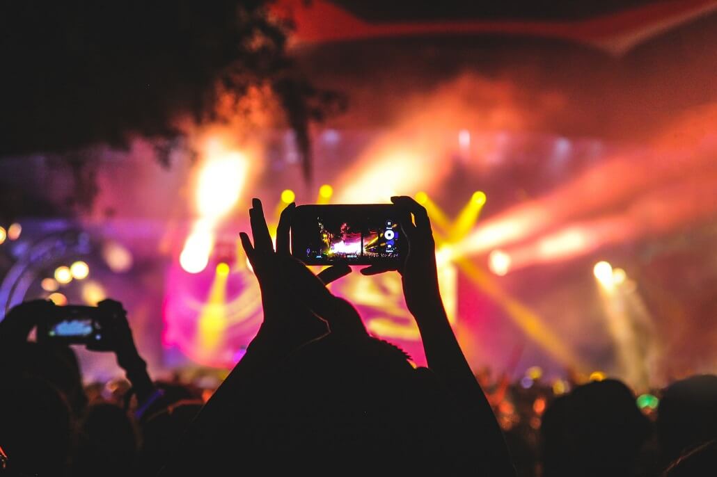 Zuschauer filmt mit einem Smartphone die Bühne eines hybriden Events