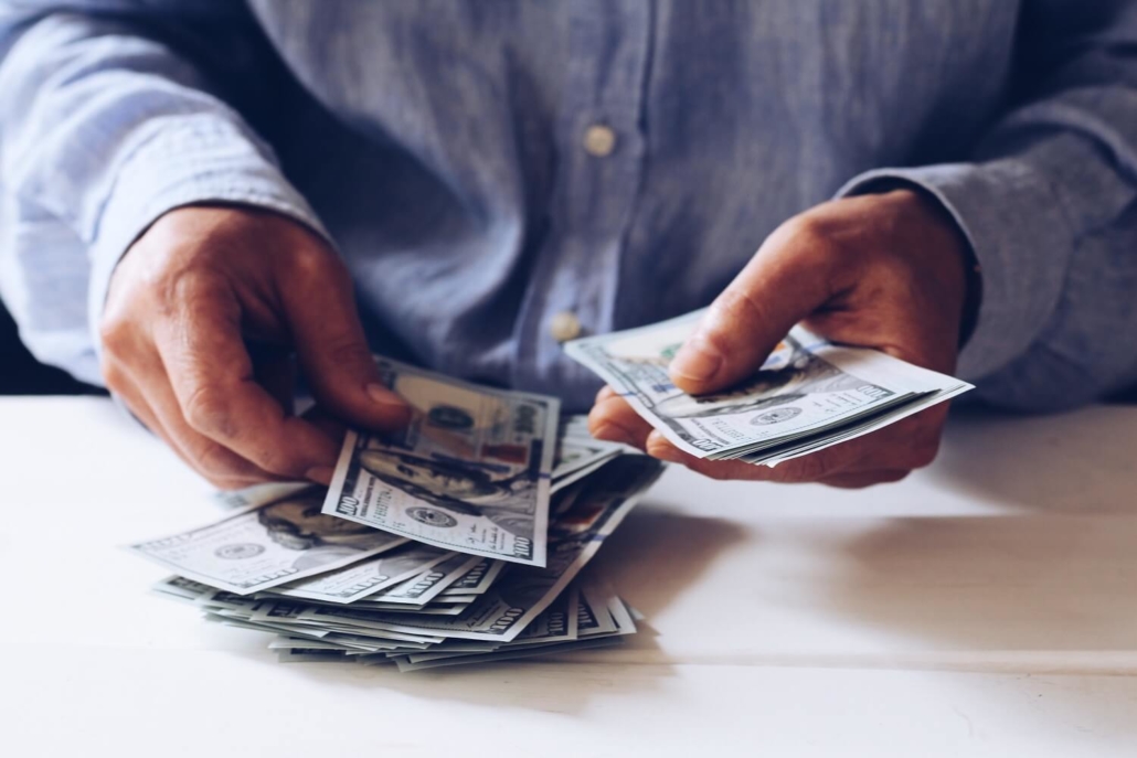 Mann zählt Geld, welches er mit der Monetarisierungsfunktion eines Podcast-Hosting-Anbieters eingenommen hat.