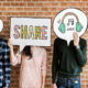 Vier Freunde halten Denkblasen mit Social Media Aufschriften hoch