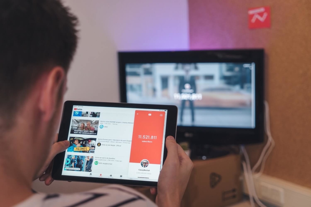 Ein Junge sitzt vor einem Fernseher und schaut sich soziale Netzwerke auf einem Tablet an