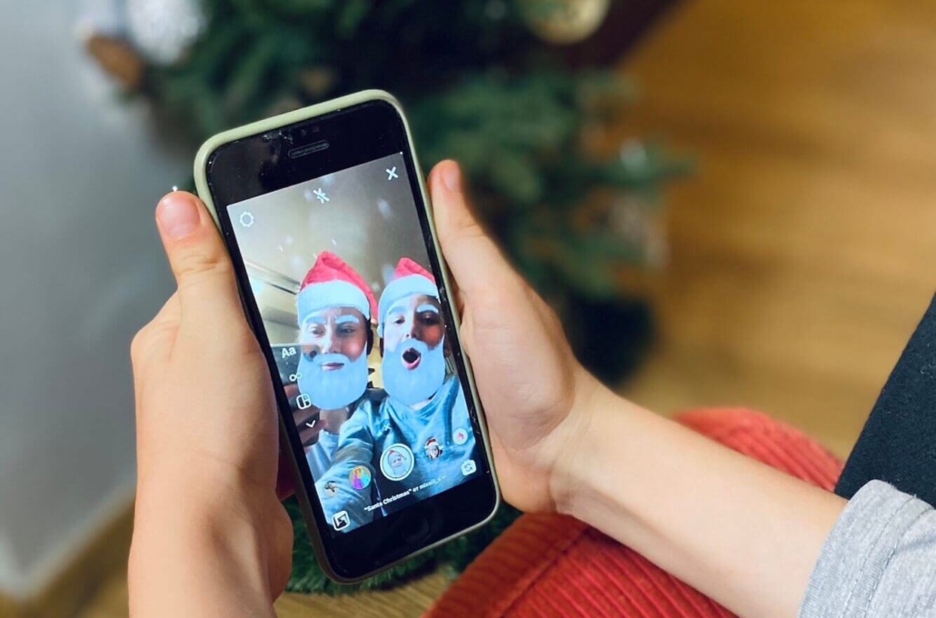 Junger Mensch hält ein Handy und macht ein Selfie mit einem Filter auf einem sozialen Netzwerk