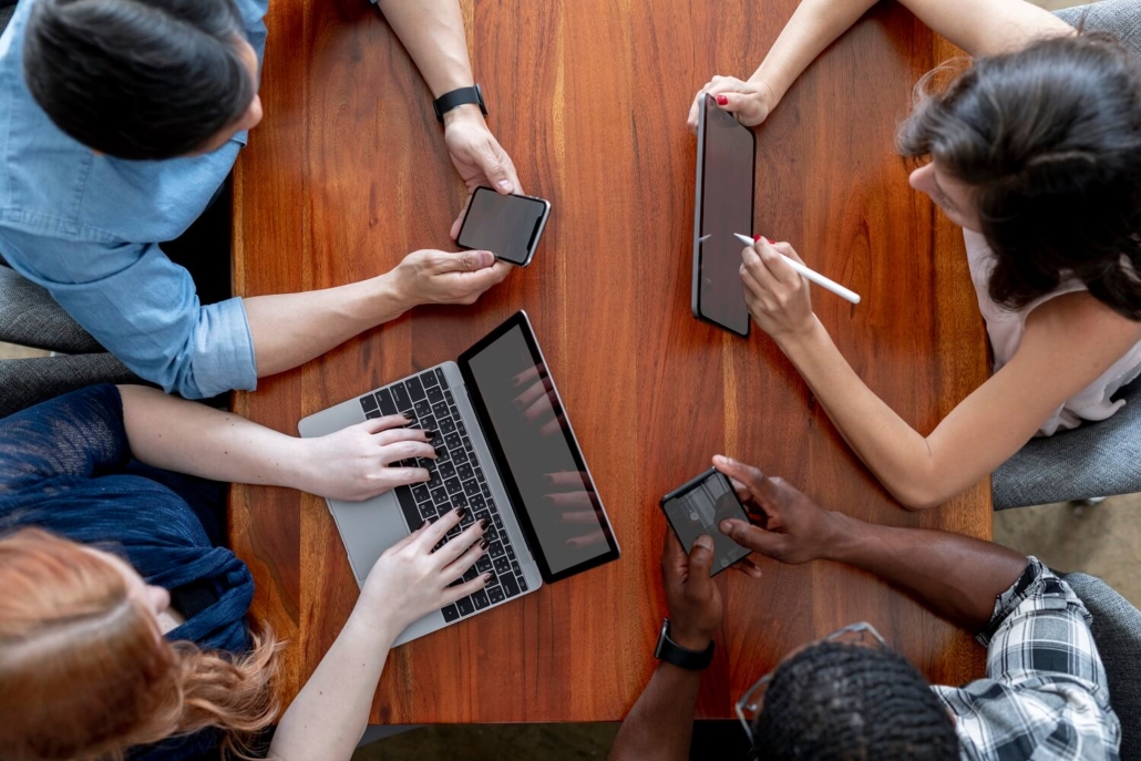 Vier Personen nehmen mit unterschiedlichen Geräten (Smartphone, Tablet & Laptop) an einem Live Commerce Event teil.