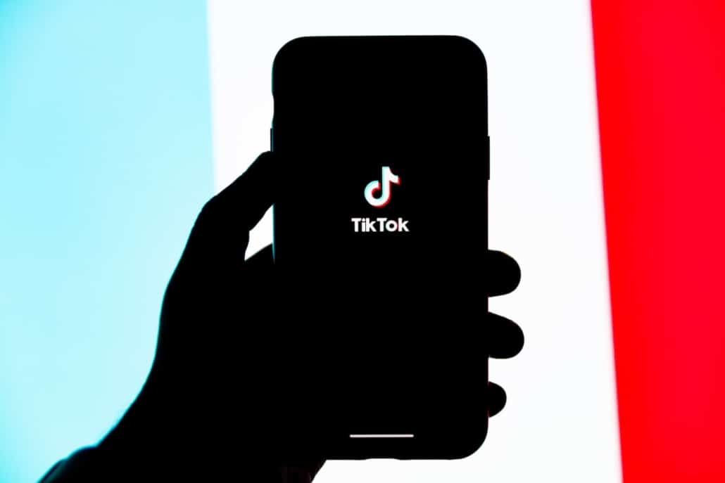 Eine Person hält ein Smartphone in der Hand, auf dem die App TikTok geöffnet wurde.