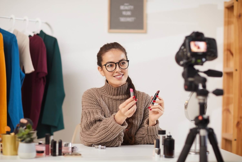 Frau mit Lippenstift gibt vor der Kamera eines Shopping-Streams ein Tutorial.