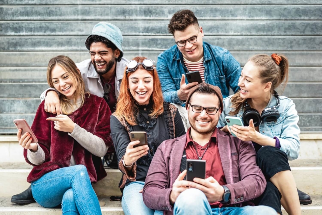 Eine Gruppe aus jungen Erwachsenen schaut sich Kurzvideos auf Smartphones an.