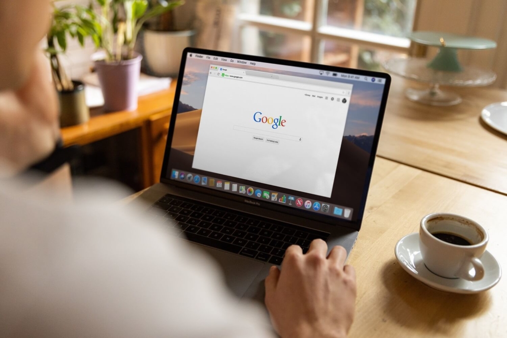 Eine Person am Schreibtisch ruft auf ihrem MacBook Google auf.