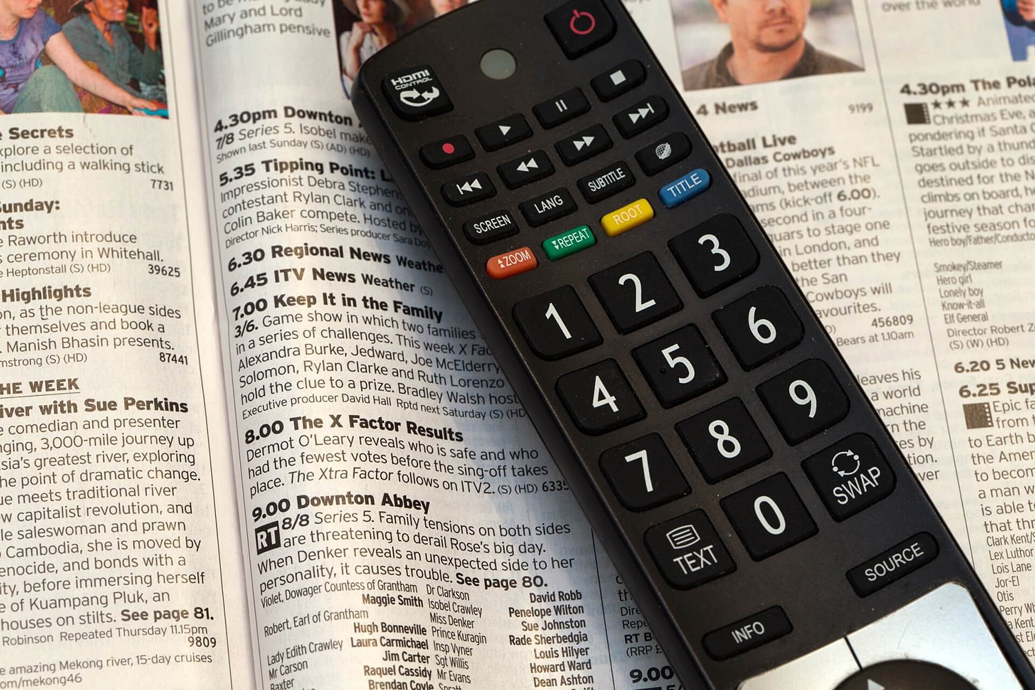Eine Fernbedienung liegt auf einer Zeitschrift mit dem TV-Programm.