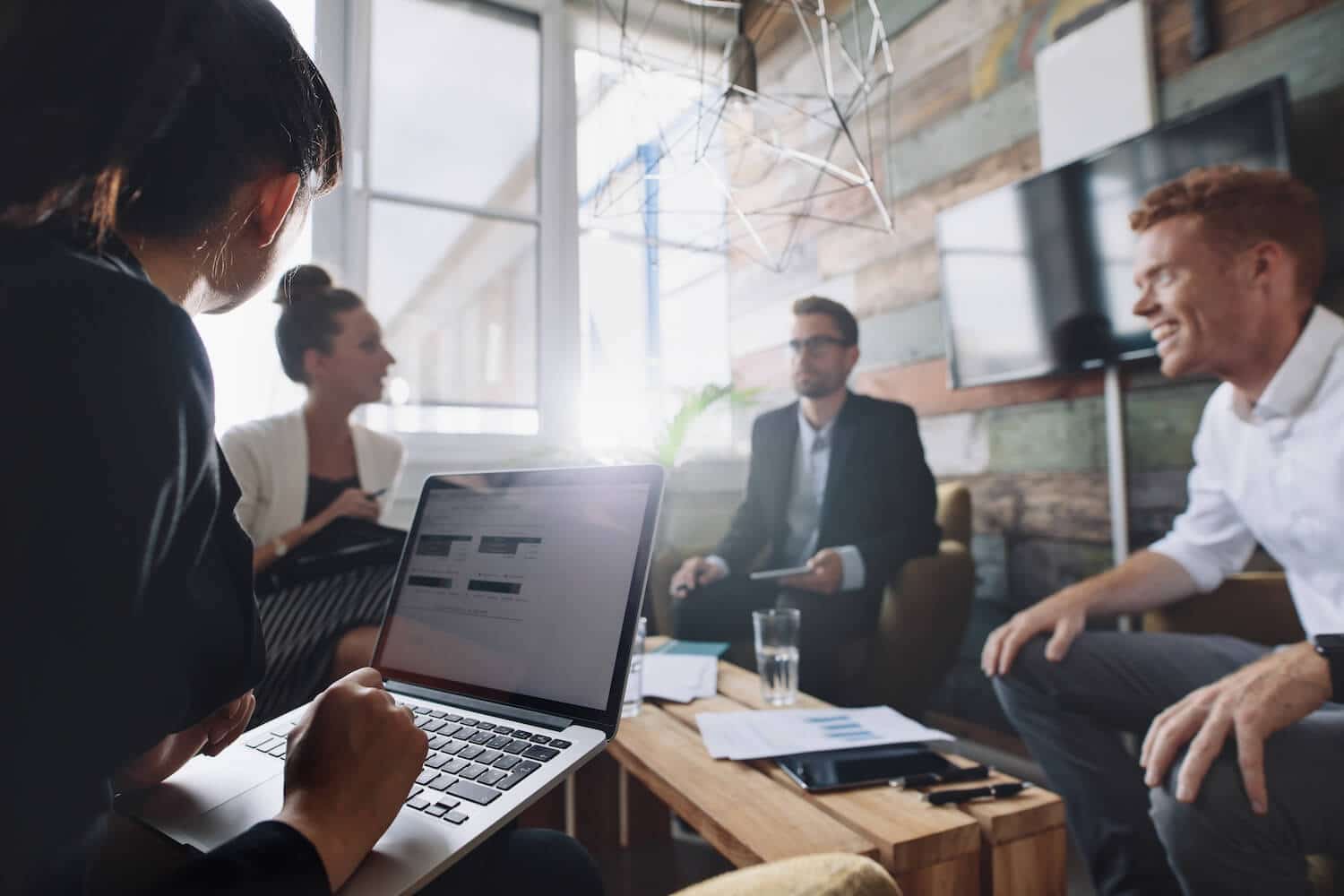 Vier Menschen sitzen in einem Büro und reden aufgeregt miteinander.