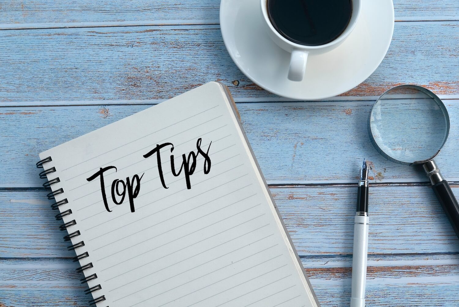 Verschiedene Gegenstände liegen auf einem Tisch neben einem Notizblock, auf dem "Top Tips" steht.
